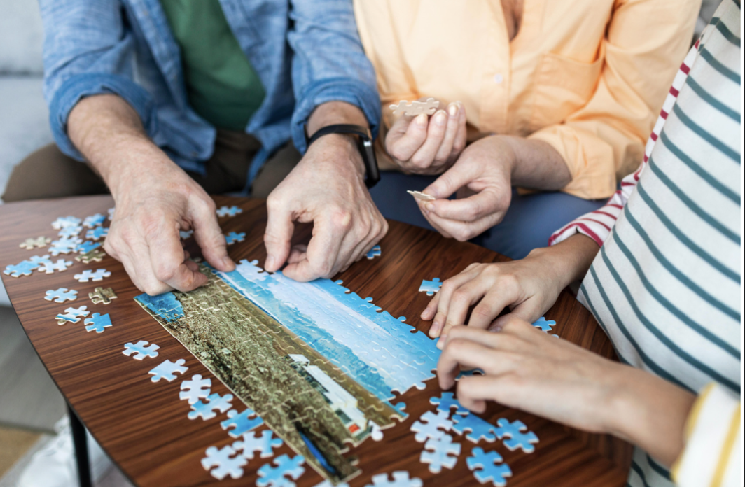 Three people doing a puzzle demonstrating how doing puzzles can have a positive impact on mental health.